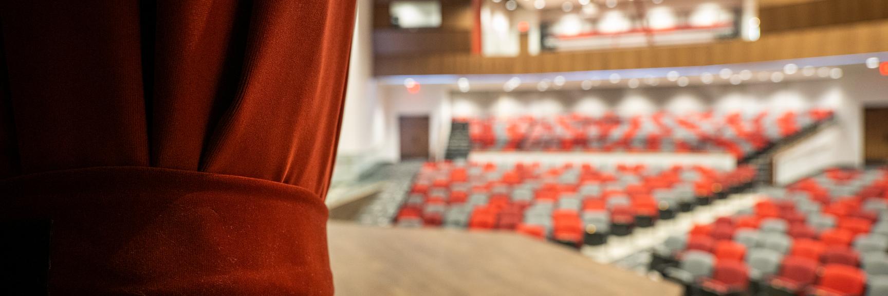  looking out at seats from behind curtain on stage at Miller Auditorium in the Aims Community College Welcome Center